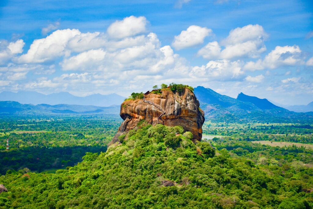 pexels-photo-13391116-13391116 Explore the iconic Sigiriya Lion Rock surrounded by lush greenery and vibrant blue skies in Sri Lanka.